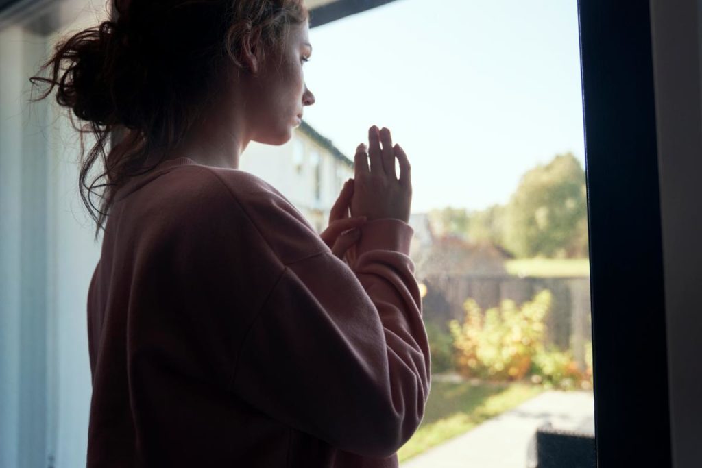 woman standing by door considers commonly abused prescription drugs