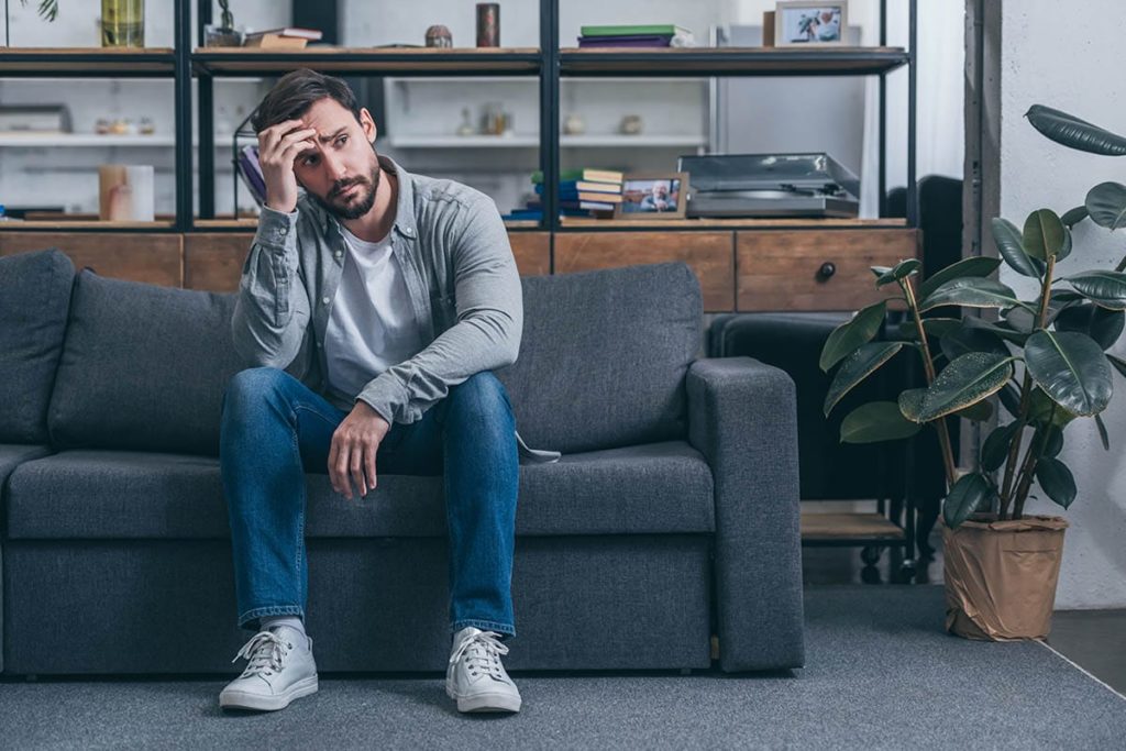 man on couch with head in hands working through the causes of benzo abuse
