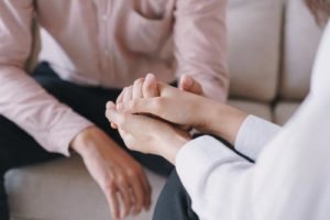 patient and therapist clasp hands in a trauma therapy program in north carolina 