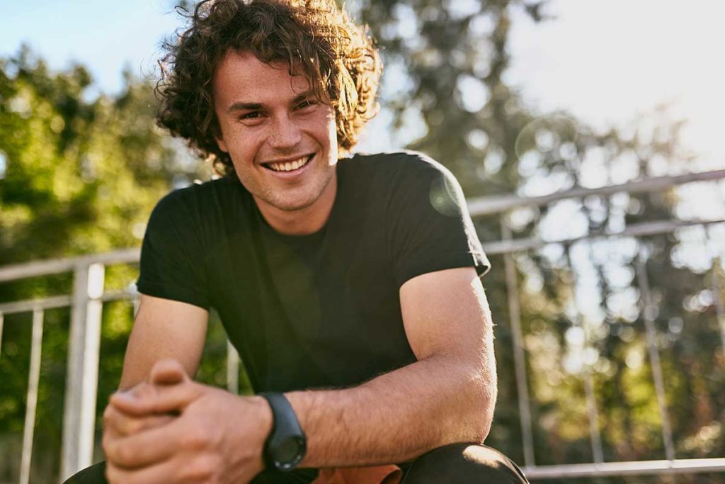 man smiling outside near fence considers how to avoid relapse