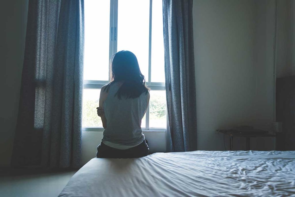 woman looks out of the window and considers how trauma and substance abuse are connected