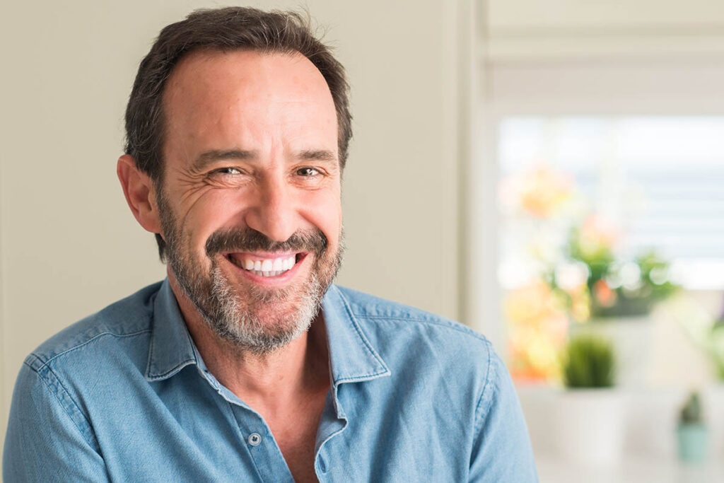 man smiles while considering the benefits of a men's rehab program