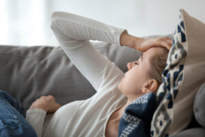 a person lays on a couch with a headache from the side effects of k2