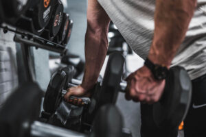 A buff man lifting dumbbells off the rack at the gym.