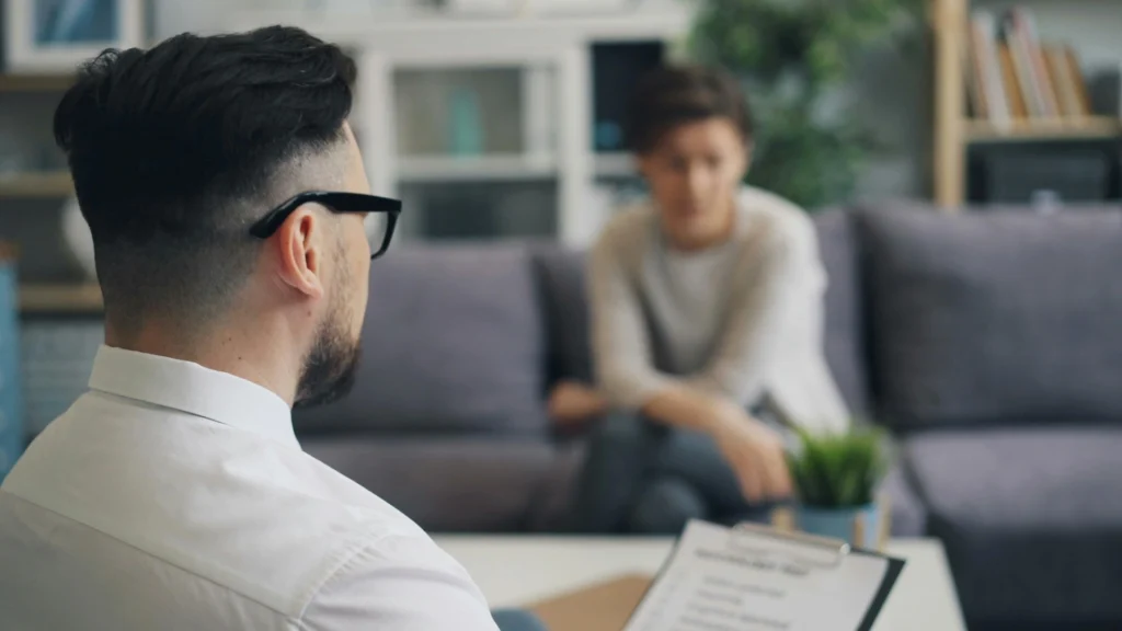 A male addiction counselor in suit in an evidence-based therapy session with a female client in a Day Intensive Outpatient Program.